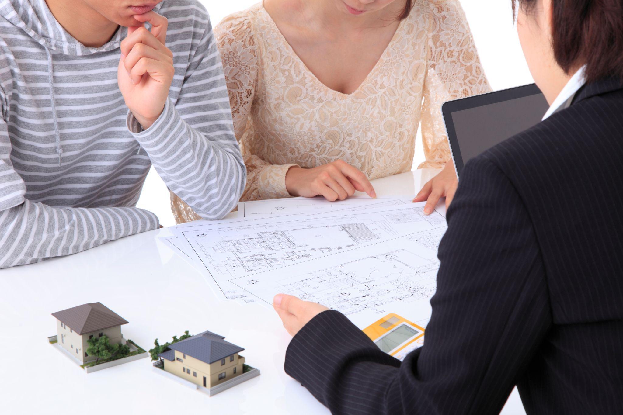 家の図面を見ながら打ち合わせをする夫婦と住宅会社スタッフ